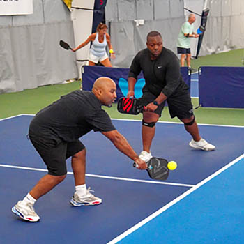 Photo of two adult males playing pickleball